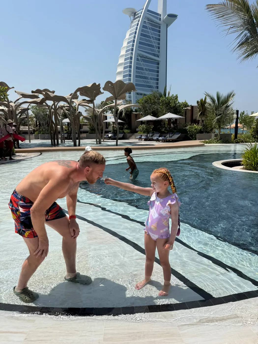 Bobby's daughter handing him a plumeria flower by the pool.