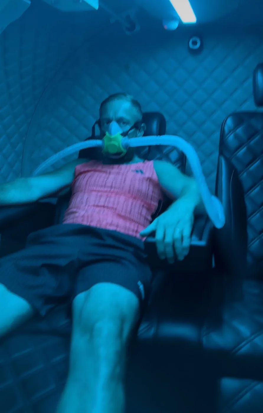 Bobby wearing an oxygen mask inside a hyperbaric chamber.