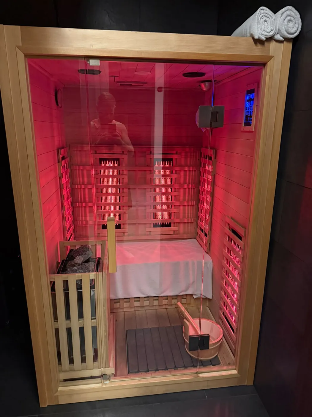 A two-person infrared sauna cabin glowing red.