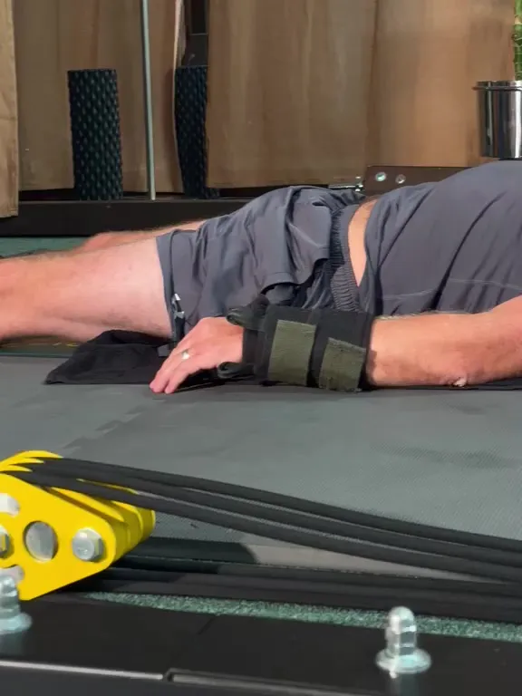 Close-up of padded cuffs strapped around Bobby's wrists as he lies on the mat.